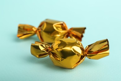 Candies in golden wrappers on light blue background, closeup