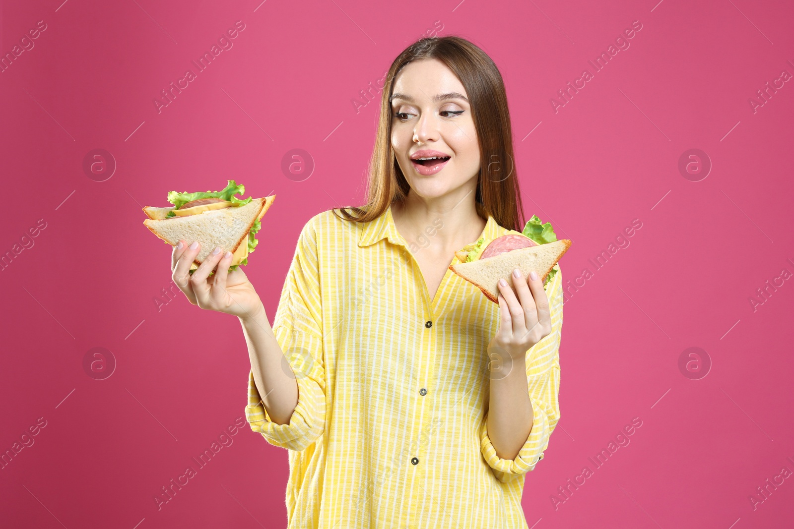 Photo of Young woman with tasty sandwiches on pink background