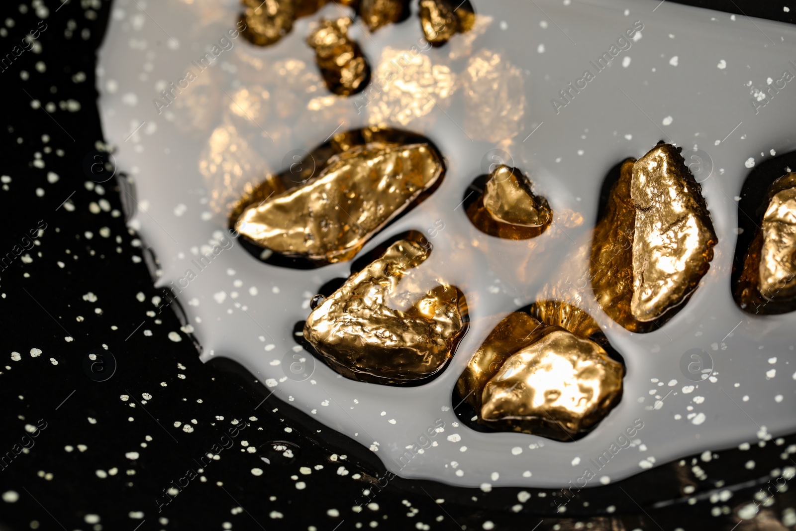 Photo of Pile of shiny gold nuggets in water, closeup view