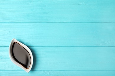 Bowl with balsamic vinegar and space for text on wooden background, top view