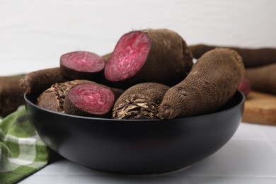 Whole and cut red beets in bowl on table, closeup