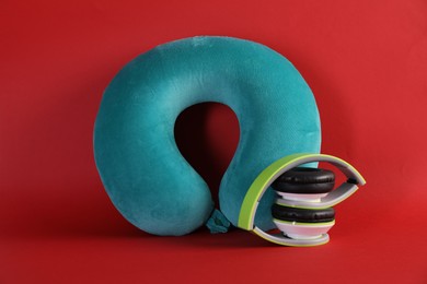 Photo of Turquoise travel pillow and headphones on red background