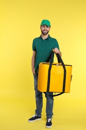 Photo of Young courier with thermo bag on color background. Food delivery service