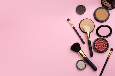 Different makeup brushes and cosmetic products on pink background, flat lay. Space for text