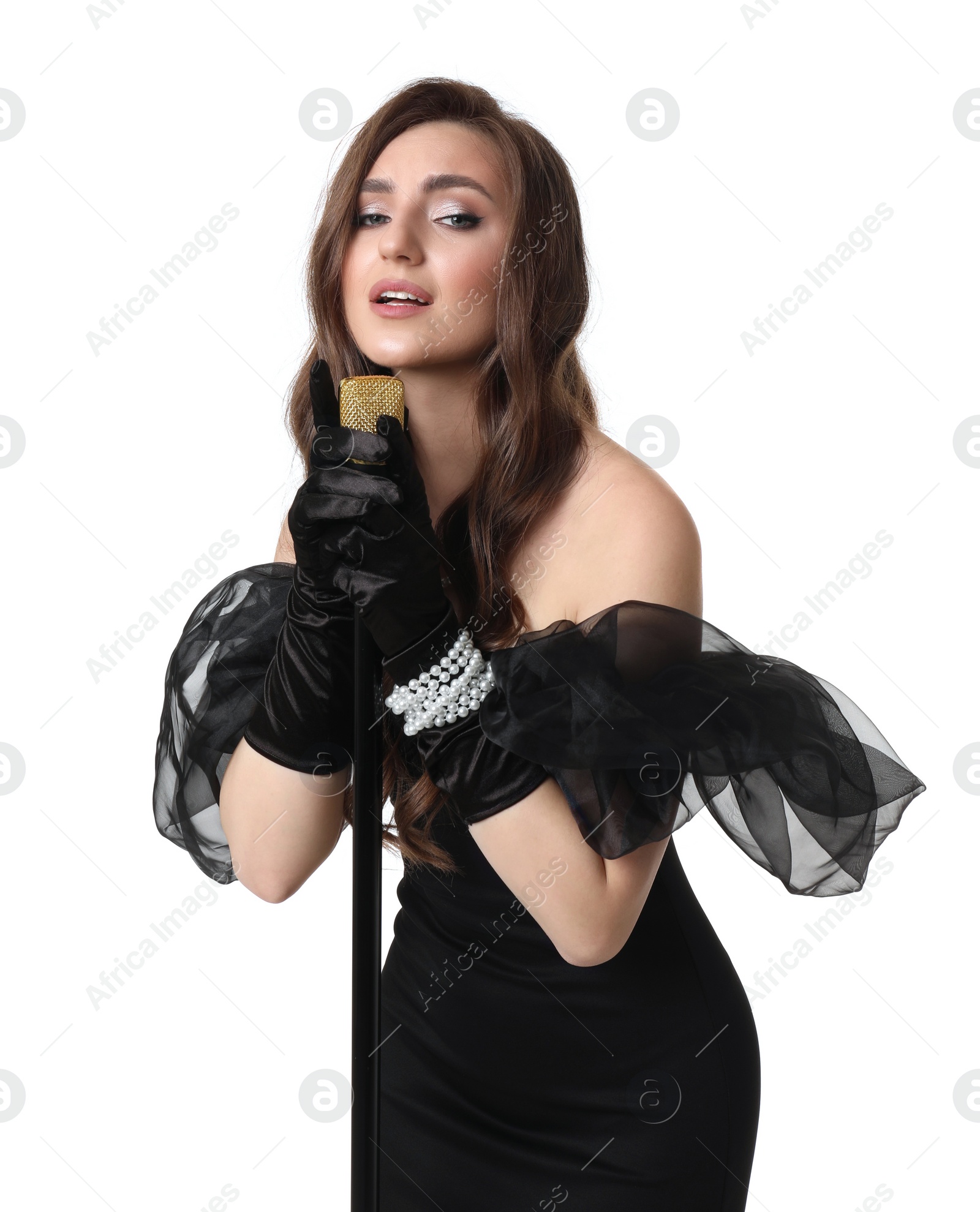 Photo of Beautiful young woman in stylish black dress with microphone singing on white background