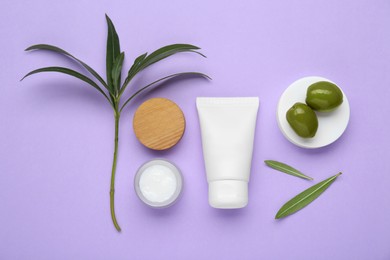 Tube and jar of cream with olive essential oil on violet background, flat lay
