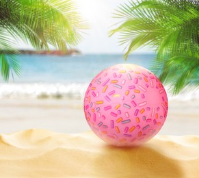 Image of Pink beach ball on sandy coast near sea