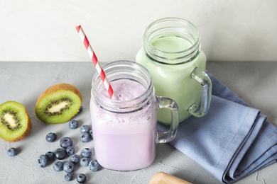 Photo of Mason jars with delicious milk shakes and ingredients on table