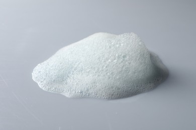 Photo of Drop of fluffy soap foam on light grey background