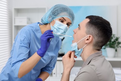 Laboratory testing. Doctor taking sample from patient's mouth with cotton swab in hospital