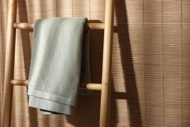 Green terry towel on wooden ladder indoors, space for text