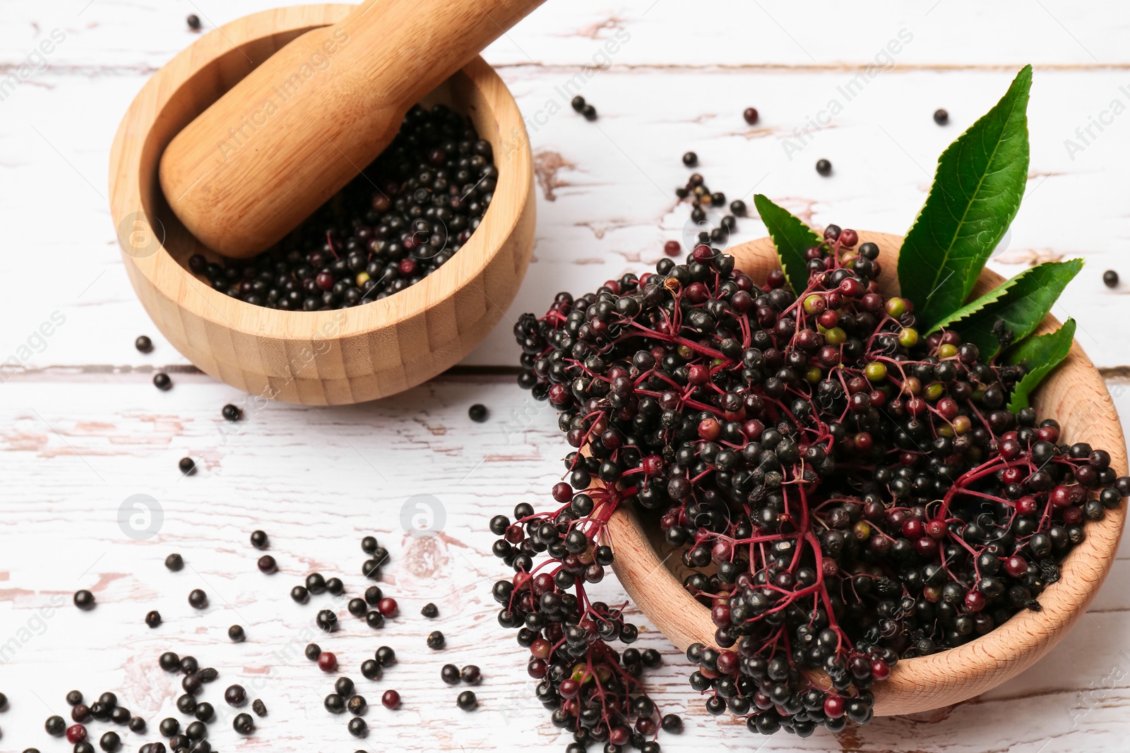 Photo of Tasty elderberries (Sambucus) on white wooden table