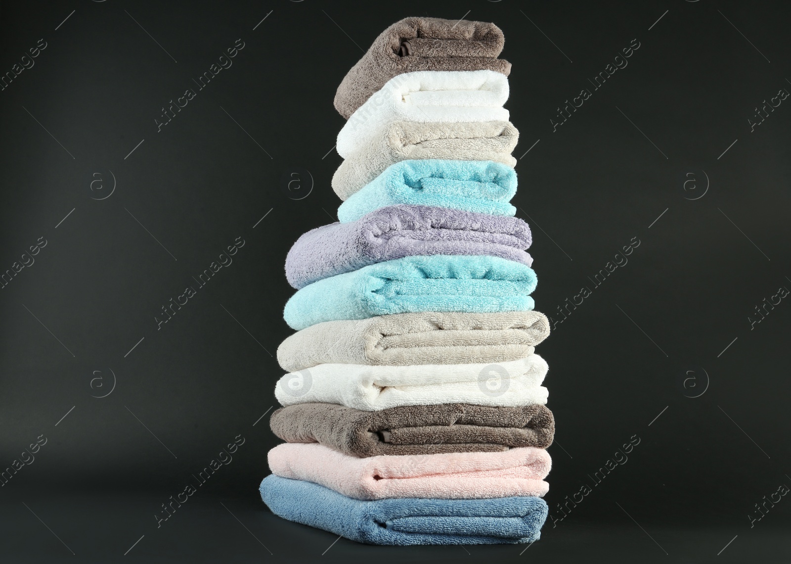 Photo of Different fresh soft terry towels on dark background