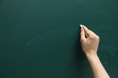 Photo of Teacher writing with chalk on green chalkboard, closeup. Space for text