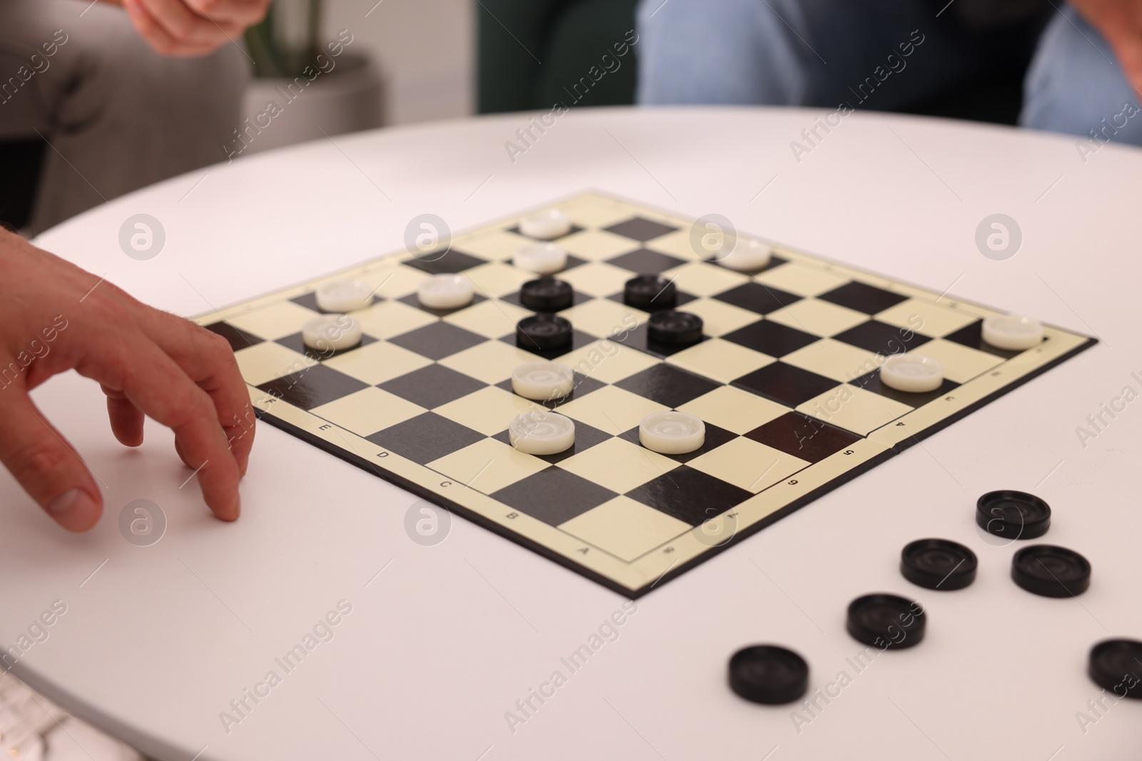 Photo of People playing checkers at white table, closeup