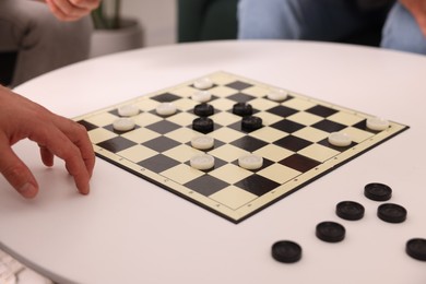 People playing checkers at white table, closeup