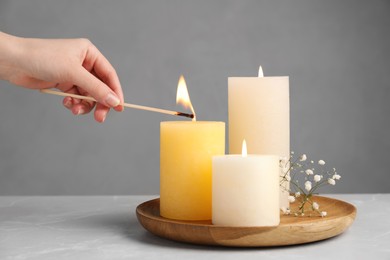 Photo of Woman lighting candle at light table, closeup