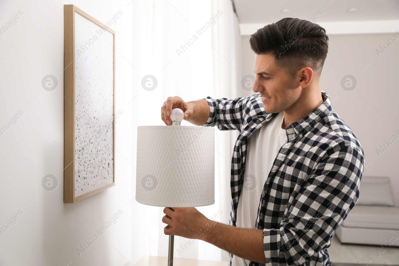 Photo of Man changing light bulb in lamp at home