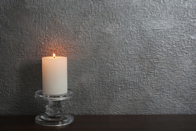 Photo of Decorative candle with stand on table against color background