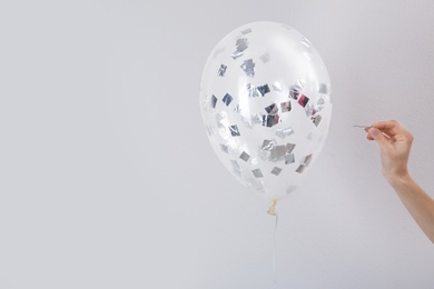 Photo of Woman piercing balloon with needle on white background, closeup