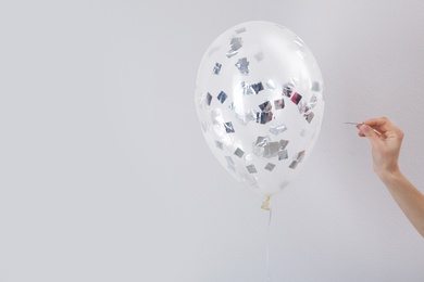 Woman piercing balloon with needle on white background, closeup