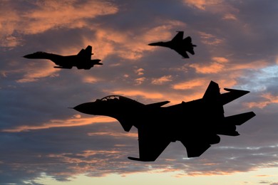 Image of Silhouettes of jet fighters in cloudy sky