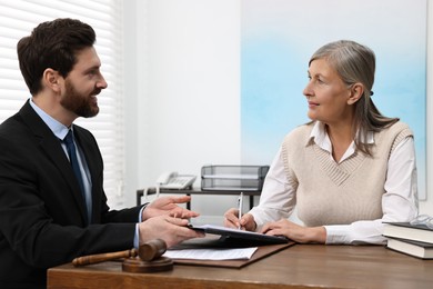 Senior woman signing document in lawyer's office