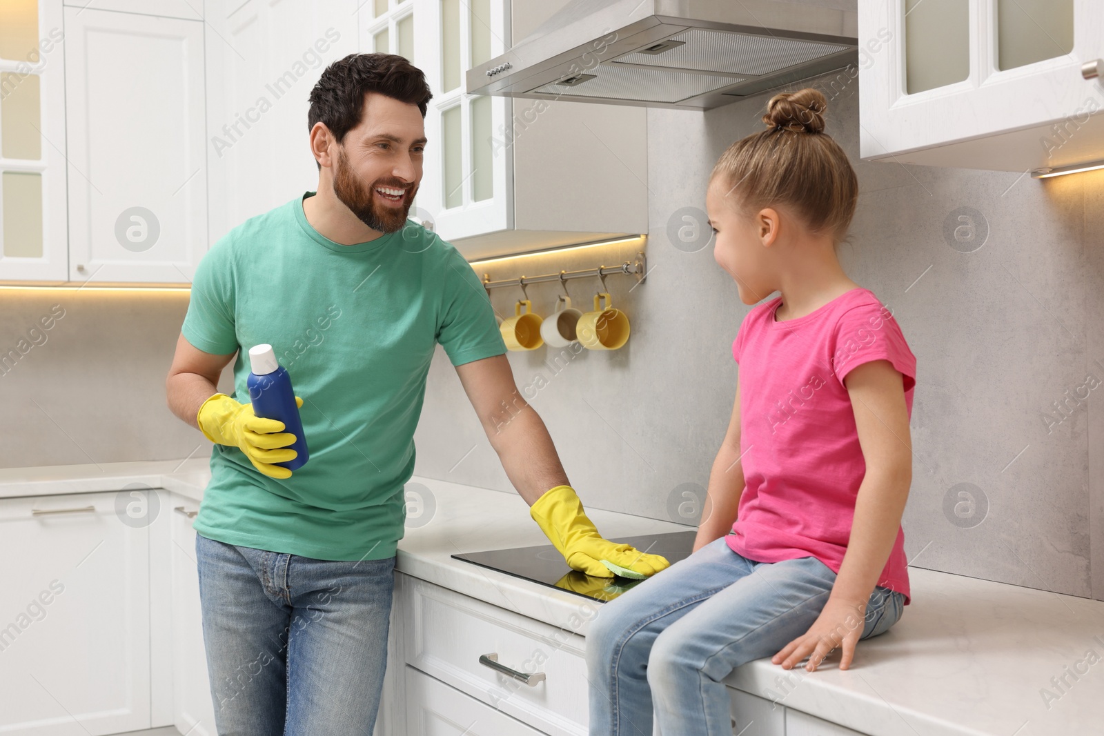 Photo of Spring cleaning. Father and daughter tidying up stove in kitchen together