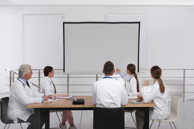 Team of doctors using video projector during conference indoors