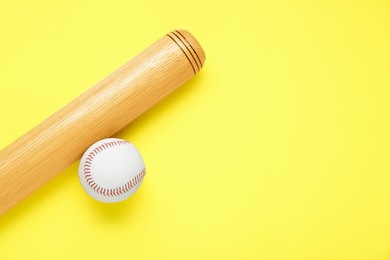 Photo of Wooden baseball bat and ball on yellow background, flat lay. Space for text