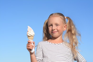 Adorable little girl with delicious ice cream against blue sky