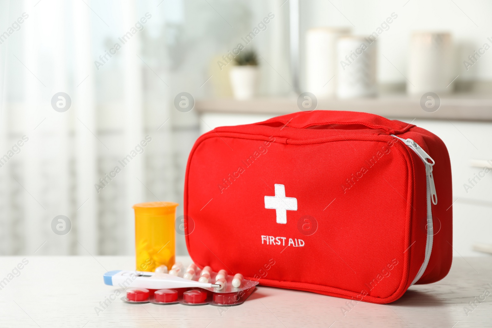 Photo of First aid kit with pills on table indoors. Space for text