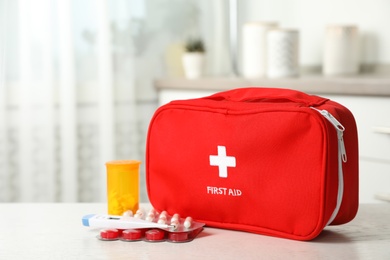 Photo of First aid kit with pills on table indoors. Space for text