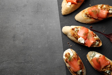 Slate plate with tasty bruschettas on grey table. Space for text