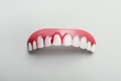 Photo of Gum model with blood on teeth against white background, top view