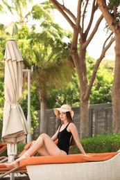 Photo of Beautiful young woman in swimsuit at resort