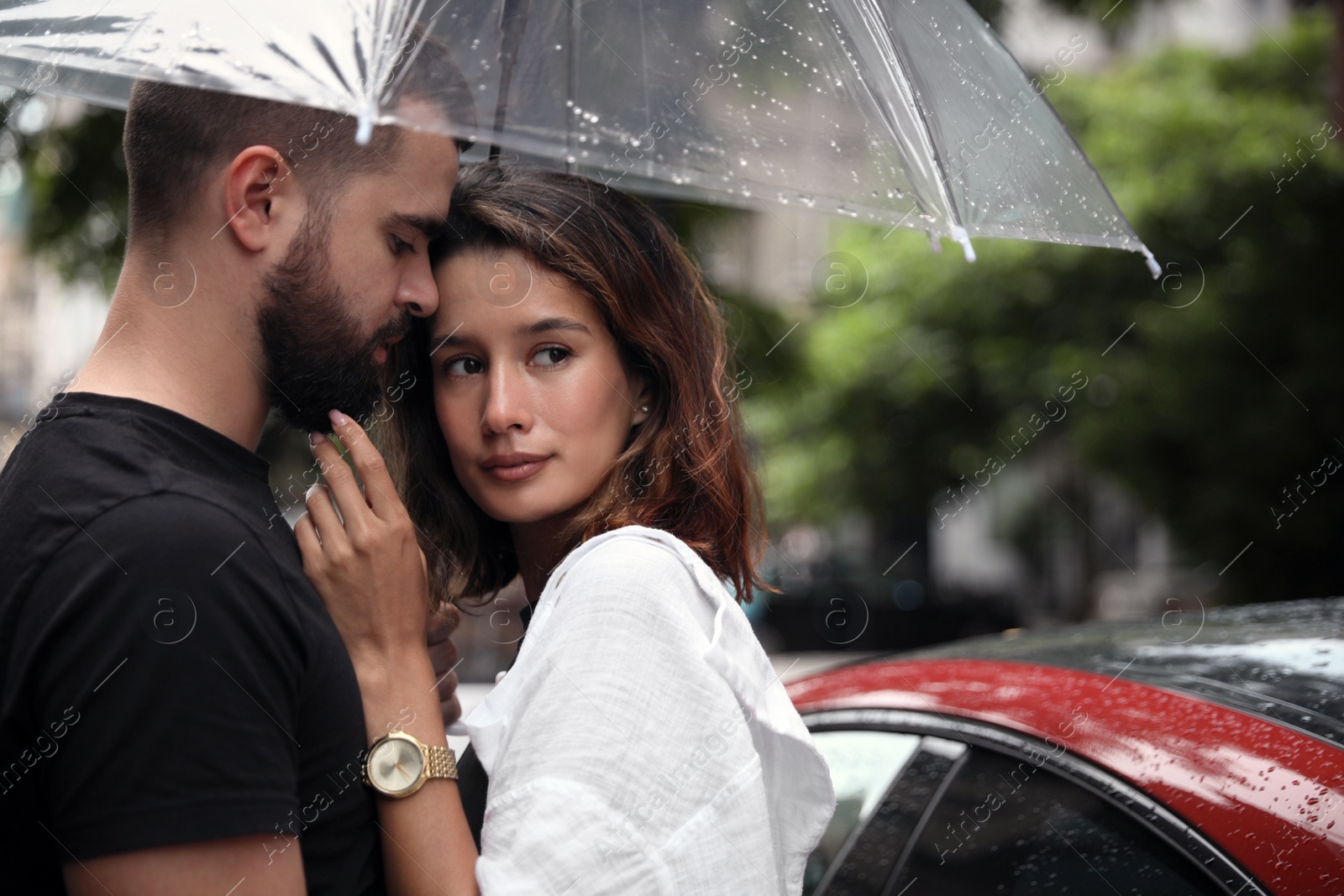 Photo of Young couple with umbrella enjoying time together under rain on city street, space for text