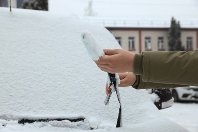 Photo of Woman cleaning wiper blade from snow outdoors, closeup