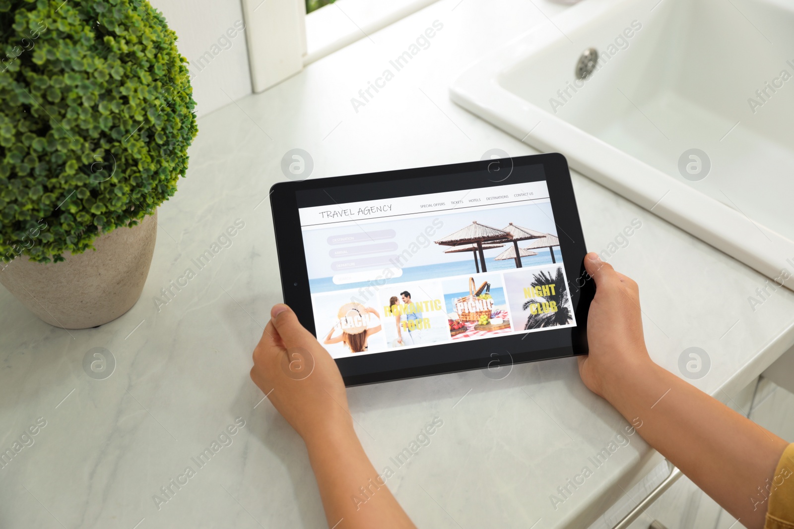 Photo of Young woman using tablet to plan trip indoors, closeup. Travel agency concept