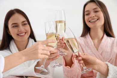 Photo of Beautiful young ladies clinking glasses of champagne at pamper party, focus on hands. Women's Day