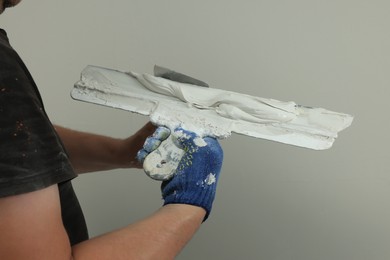 Professional worker putting plaster on putty knife indoors, closeup