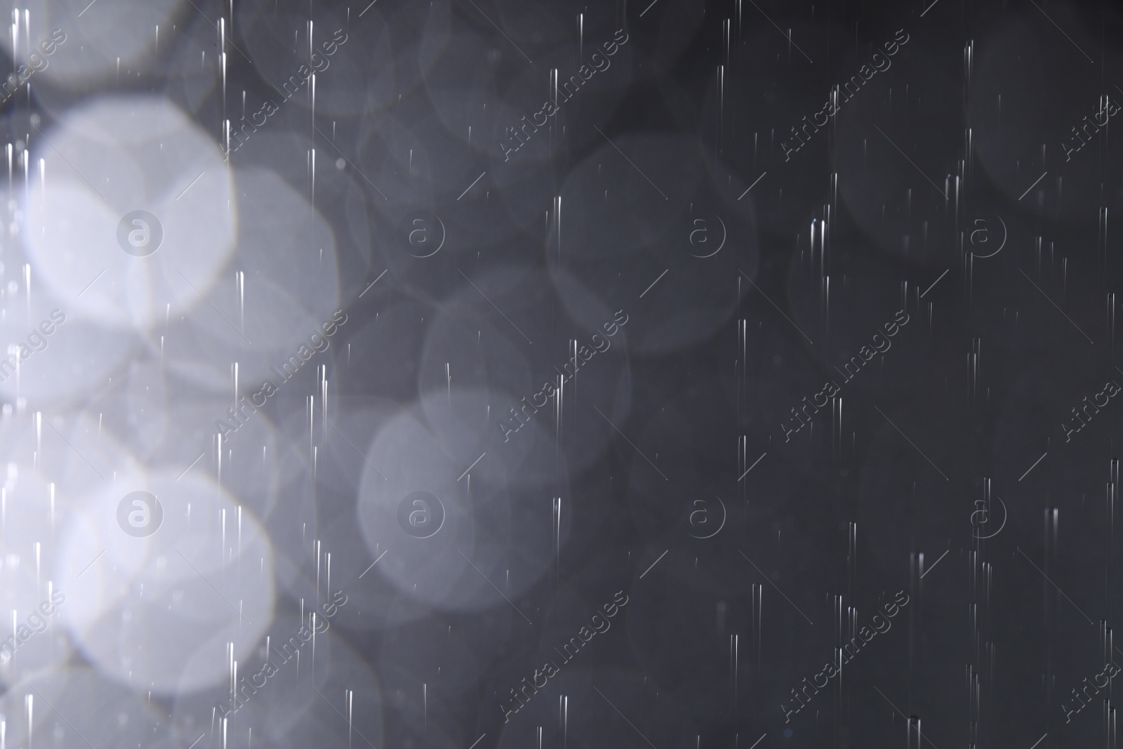 Photo of Rain drops falling down against dark background