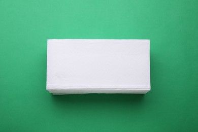 Photo of Stack of clean tissue towels on green background, top view