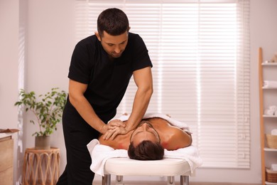 Photo of Man receiving professional massage on couch in spa salon