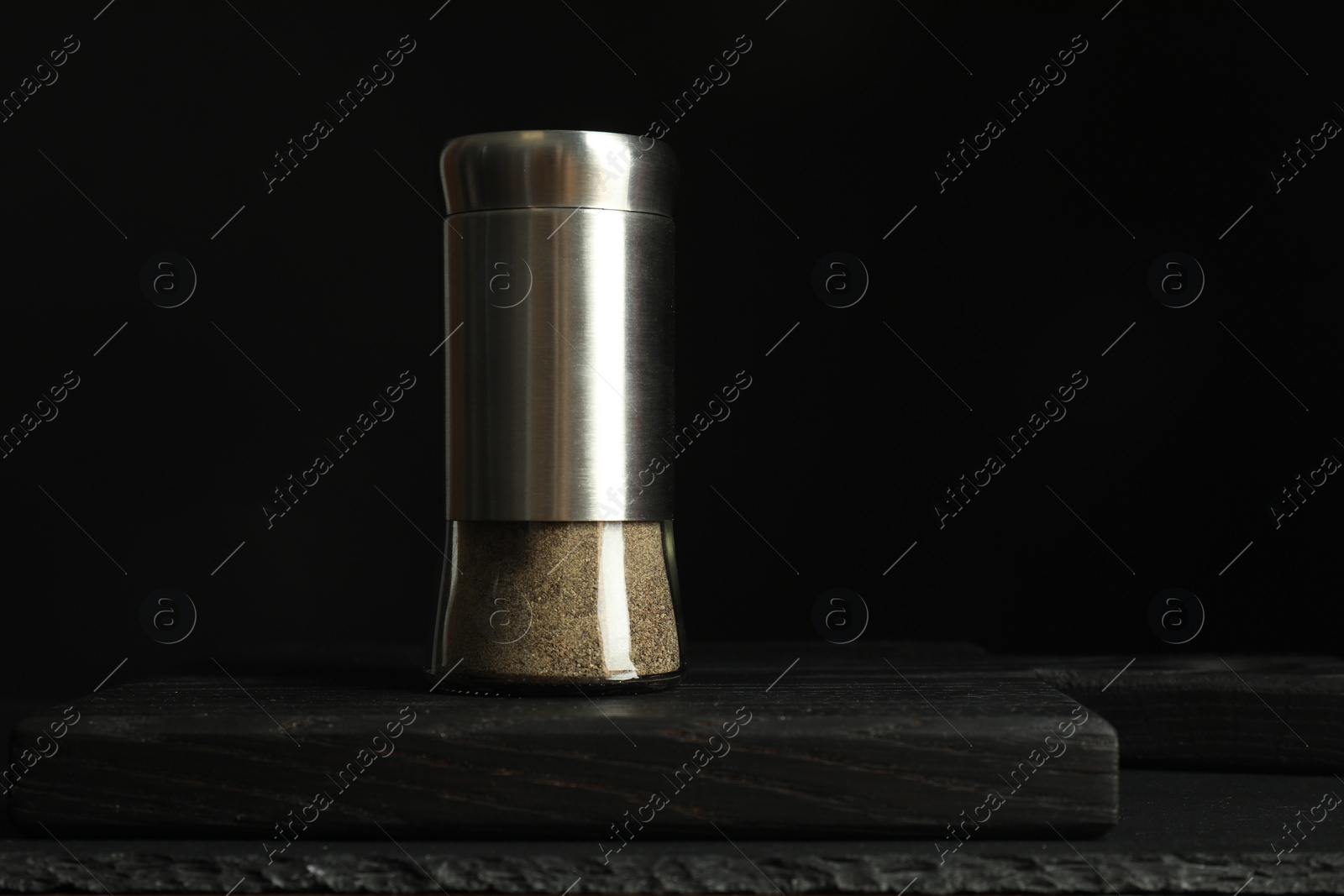 Photo of Pepper shaker on black table. Space for text