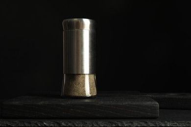 Pepper shaker on black table. Space for text