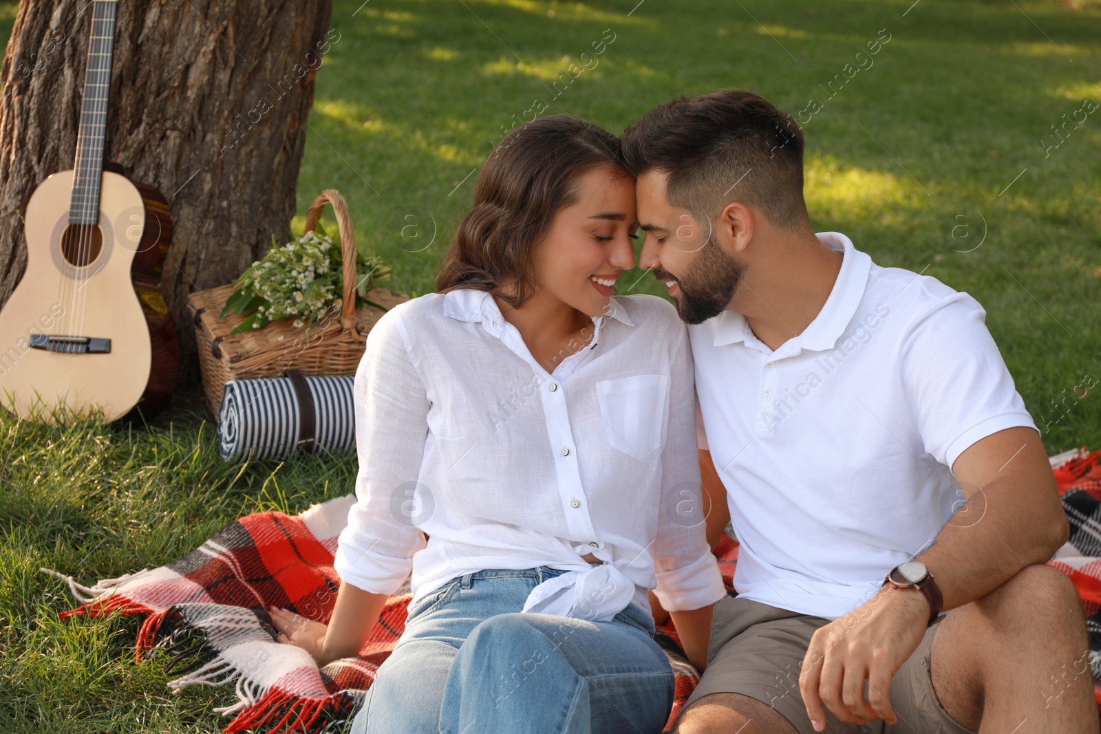 Photo of Lovely couple enjoying time together on picnic plaid in park