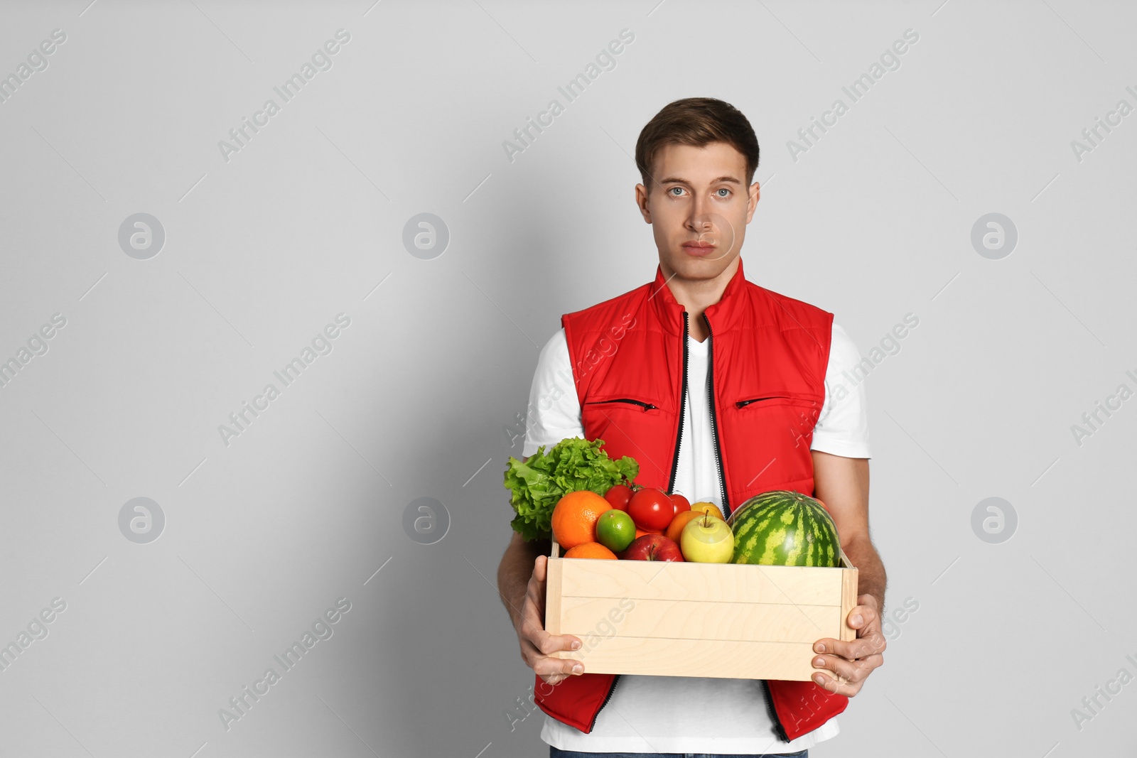 Photo of Courier with fresh products on light background, space for text. Food delivery service