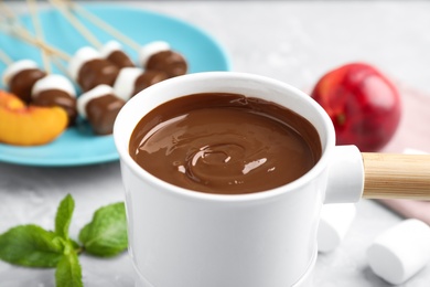 Photo of Fondue pot with milk chocolate on light table, closeup