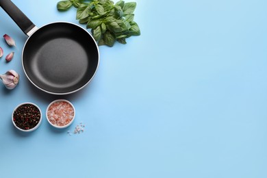 Flat lay composition with frying pan and fresh products on light blue background, space for text